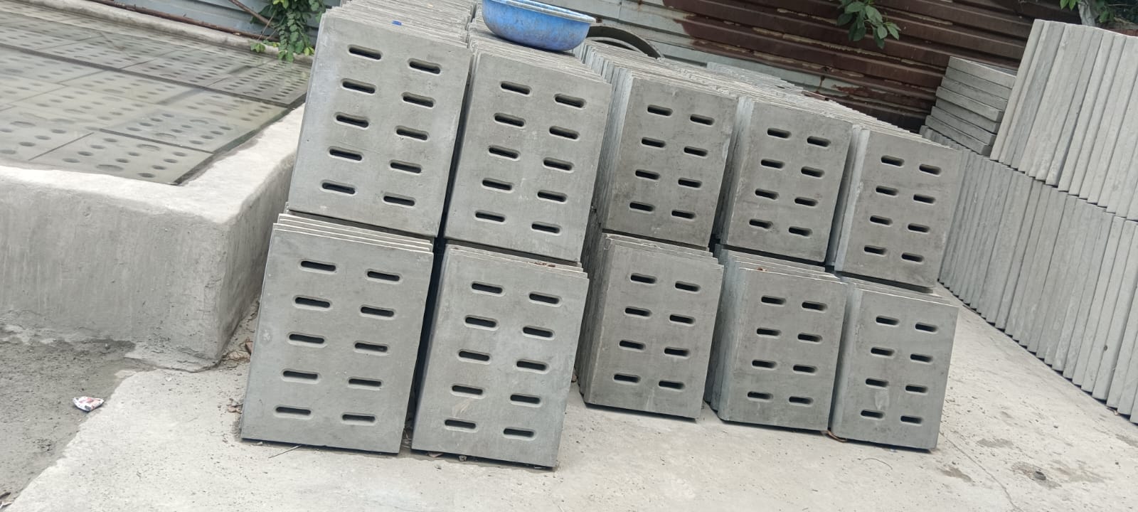 Sustainable RCC concrete drainage covers with oval slots, designed for eco-friendly infrastructure, Eco-conscious RCC hole covers made with durable cement, ideal for green construction projects, Environment-friendly RCC drain covers stacked at production site, promoting sustainable urban development