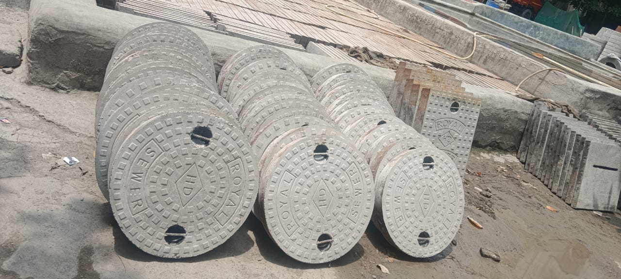 RCC round manhole cover on road,Cast iron manhole cover with patterned surface, Installed concrete manhole cover in urban area, Heavy-duty manhole cover for drainage system